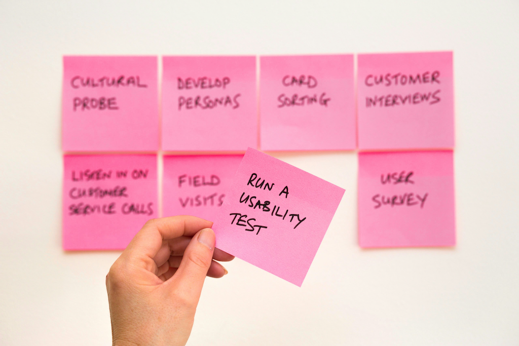 Post-its mit dem Text "Run a usability test" in der Hand