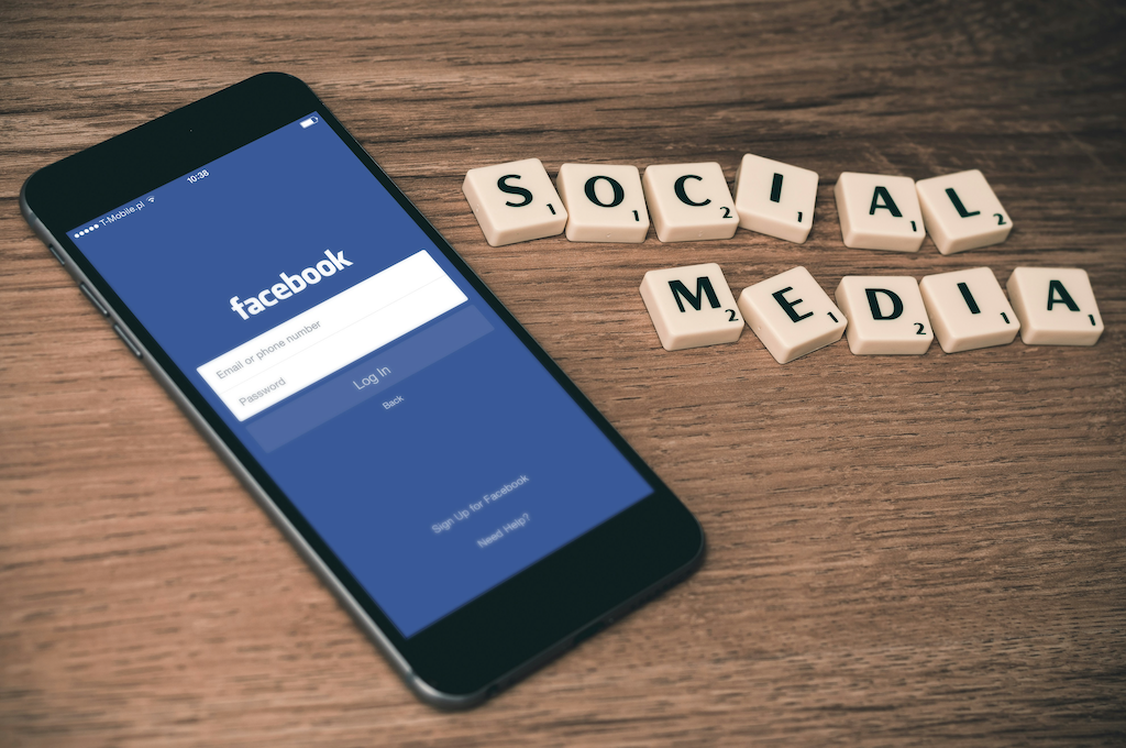 Handy mit Facebook-Page und Social Media in Buchstaben daneben